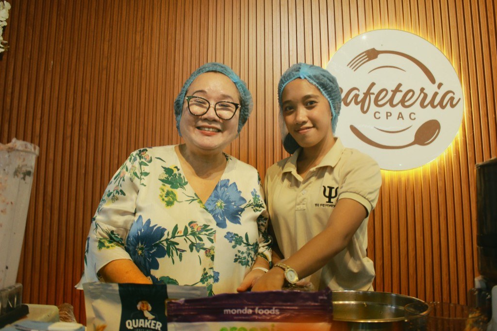 Dr. Neda June D. Salazar and a psychology student prepare breakfast smoothies at the CPAC cafeteria